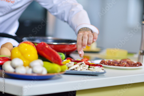 mature chef preparing a meal with various vegetables and meat