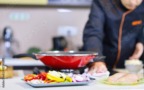 mature chef preparing a meal with various vegetables and meat