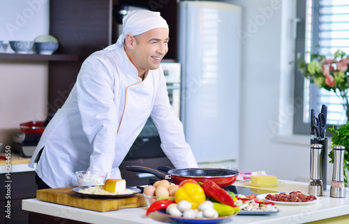 mature chef preparing a meal with various vegetables and meat