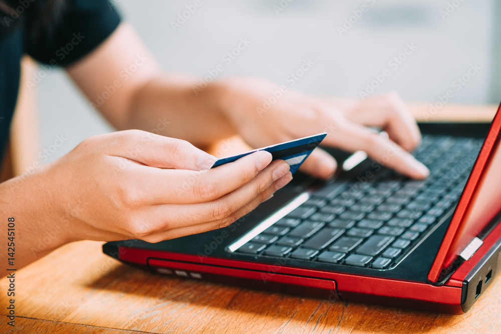 Woman's hands holding credit card and using laptop, online shopping concept