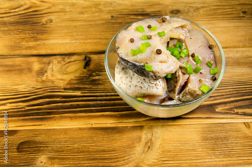 Marinated carp in glass bowl on wooden table