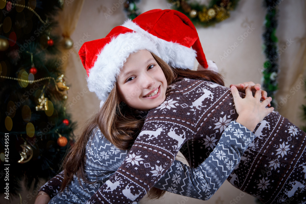 Mother hugging daughter under Christmas tree Mother hugging daughter under Christmas tree