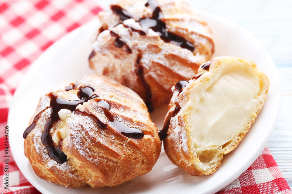 Homemade profiteroles with cream on white wooden table