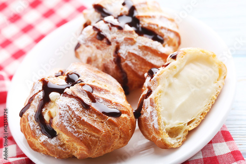 Homemade profiteroles with cream on white wooden table