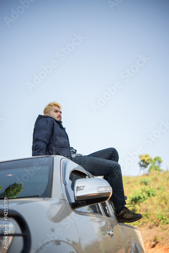 Young adventure hiker man enjoy with nature sitting on his truck.