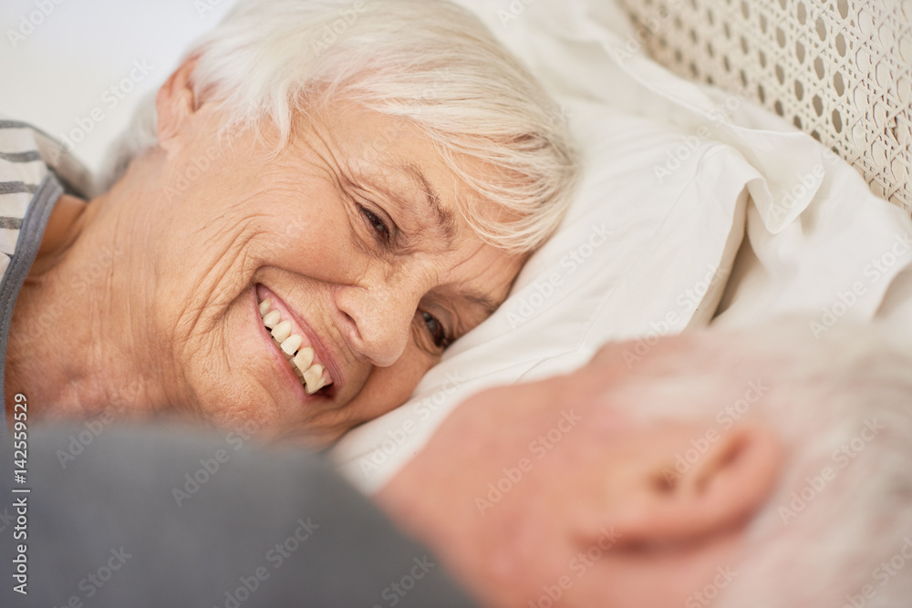 Content senior couple smiling warmly at each other in bed Content senior couple smiling warmly at each other in bed
