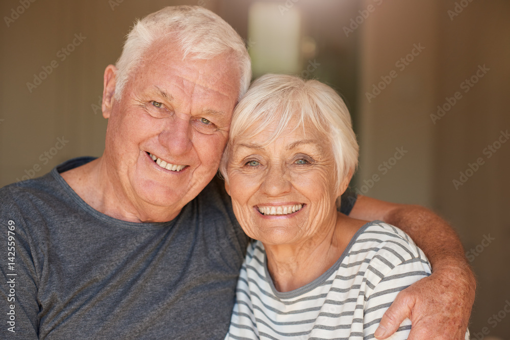 Content senior couple smiling and sitting together at home Content senior couple smiling and sitting together at home