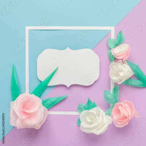 square frame with color paper flowers on the blue and violet background. Flat lay. Nature concept
