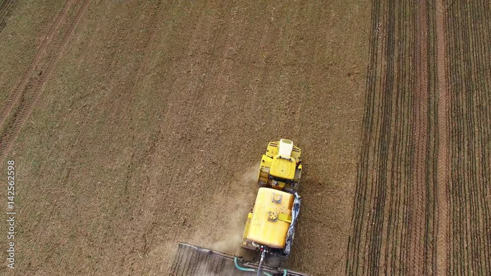 Aerial view of brown field with sowing machine. Growing and crop care on springtime. Agriculture from above. Seasonal work on Czech countryside. Czech Republic, Central Europe. Aerial view of brown field with sowing machine. Growing and crop care on springtime. Agriculture from above. Seasonal work on Czech countryside. Czech Republic, Central Europe.