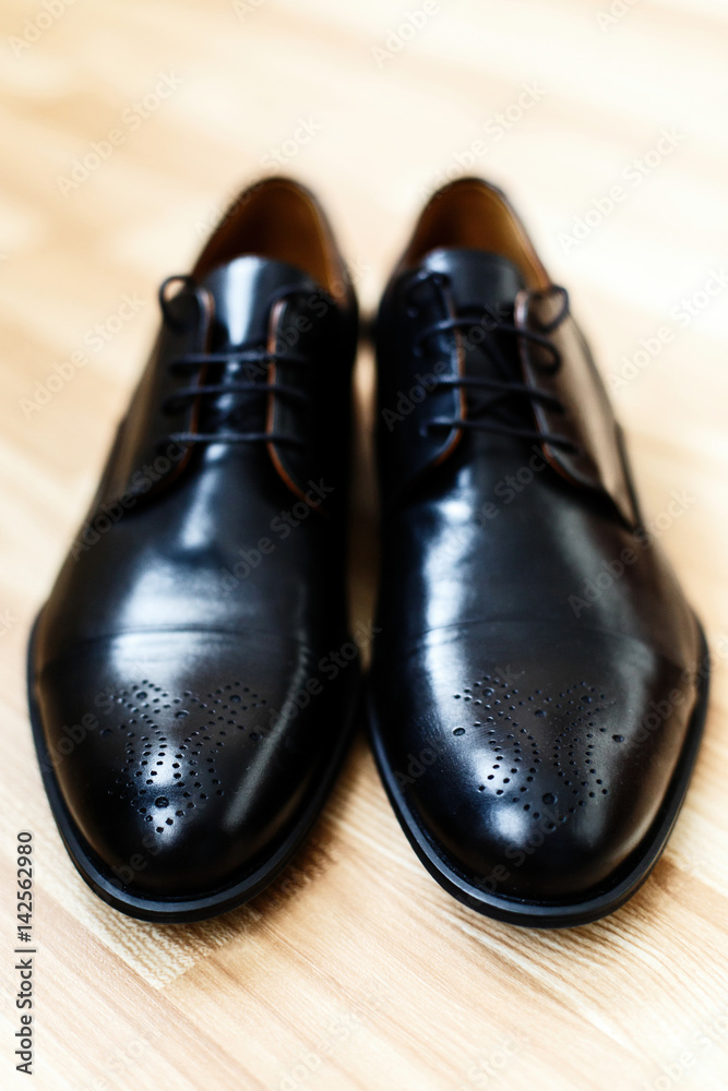 Look from above at black leather men shoes standing on beige floor Look from above at black leather men shoes standing on beige floor