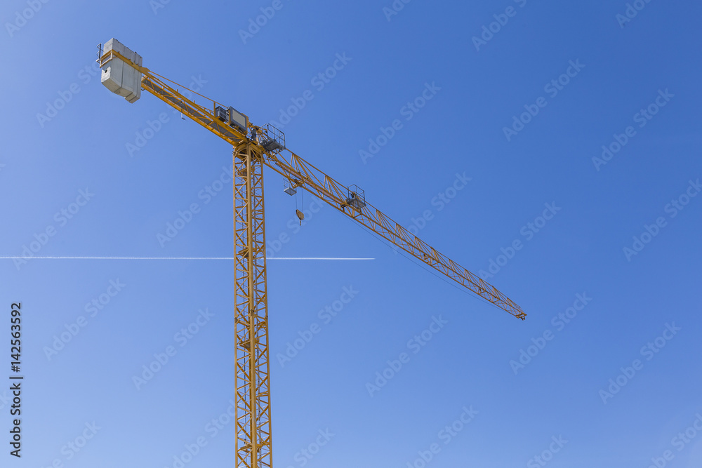 high crane on clear blue sky with a passing aircraft high crane on clear blue sky with a passing aircraft