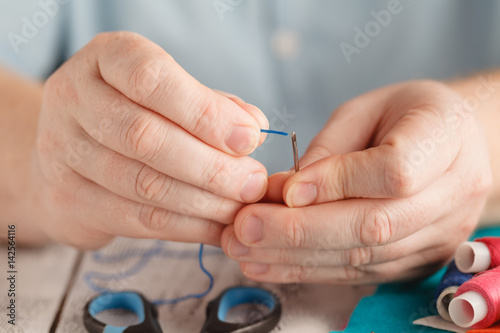 Insert the thread in needle by man hand
