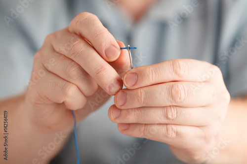 Insert the thread in needle by man hand