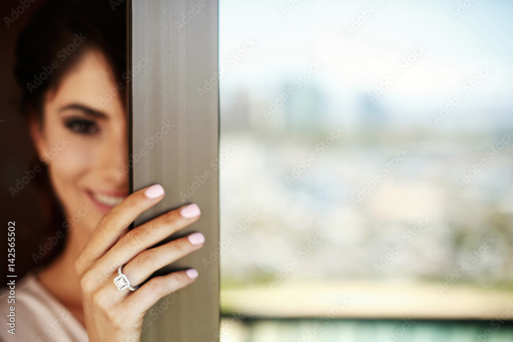 Fototapeta premium Brunette woman holds her hand with wedding ring on balcony door