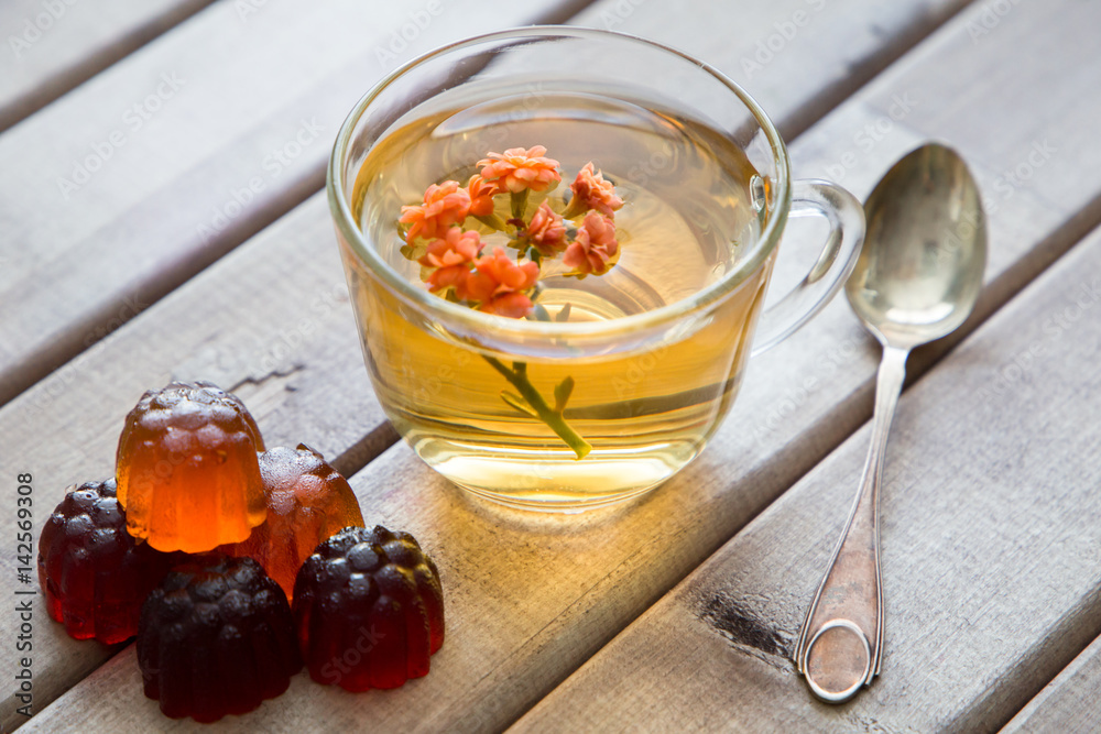 Closeup of cup of tea with bright flower on wooden table with spoon and Marmalade. still life with tea cup. Closeup of cup of tea with bright flower on wooden table with spoon and Marmalade. still life with tea cup.