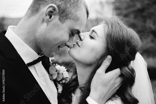 Groom holds bride's head tender while she leans to him for a kiss