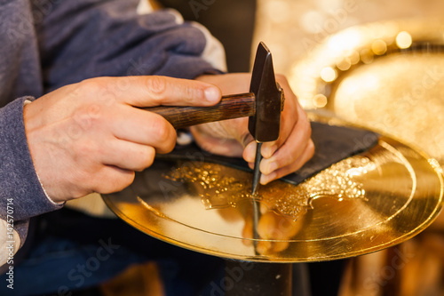 Fotografija Craftsman hands with hammer working on a golden plate