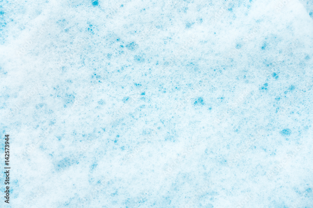 White detergent foam on blue as background.