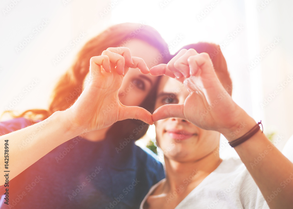 Loving couple at home making heart shape with hands Loving couple at home making heart shape with hands