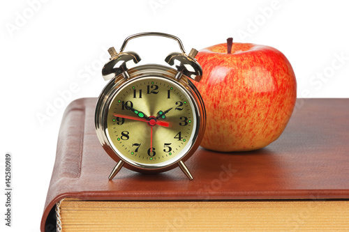 golden alarm clock and apple on the book isolated