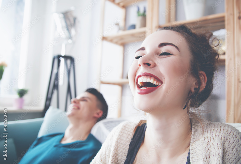 Couple at home enjoying on sofa and laughing while watching something