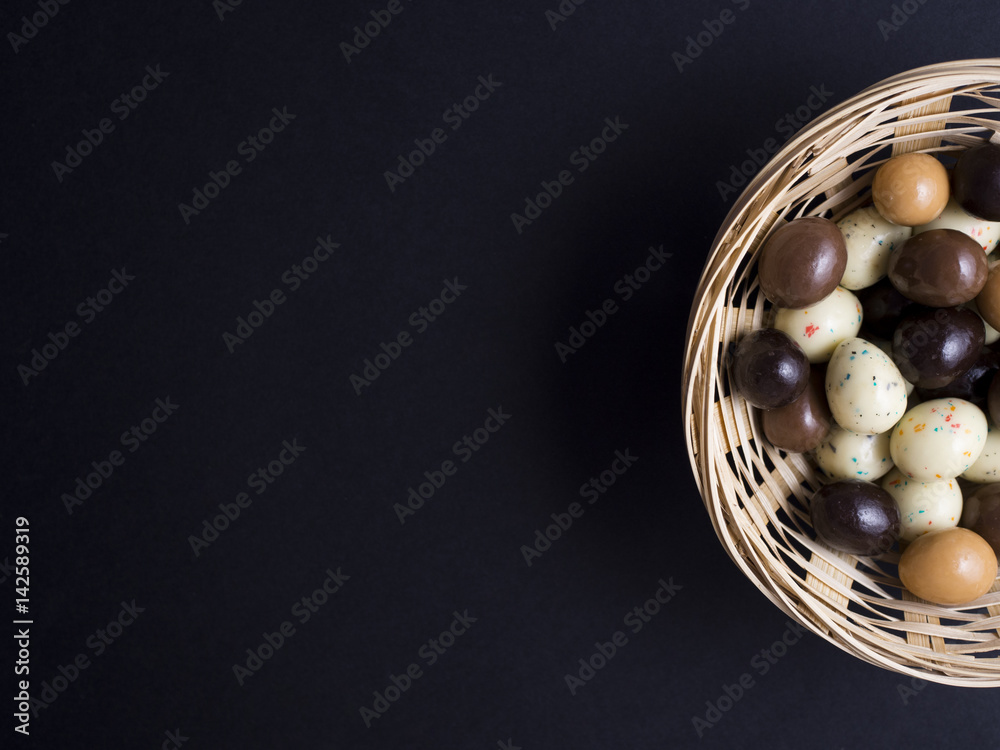 Chocolate easter eggs in wooden basket isolated on black background