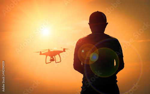 Silhouette man playing with the drone.