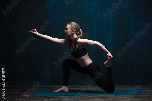 Young flexible woman practicing yoga indoors