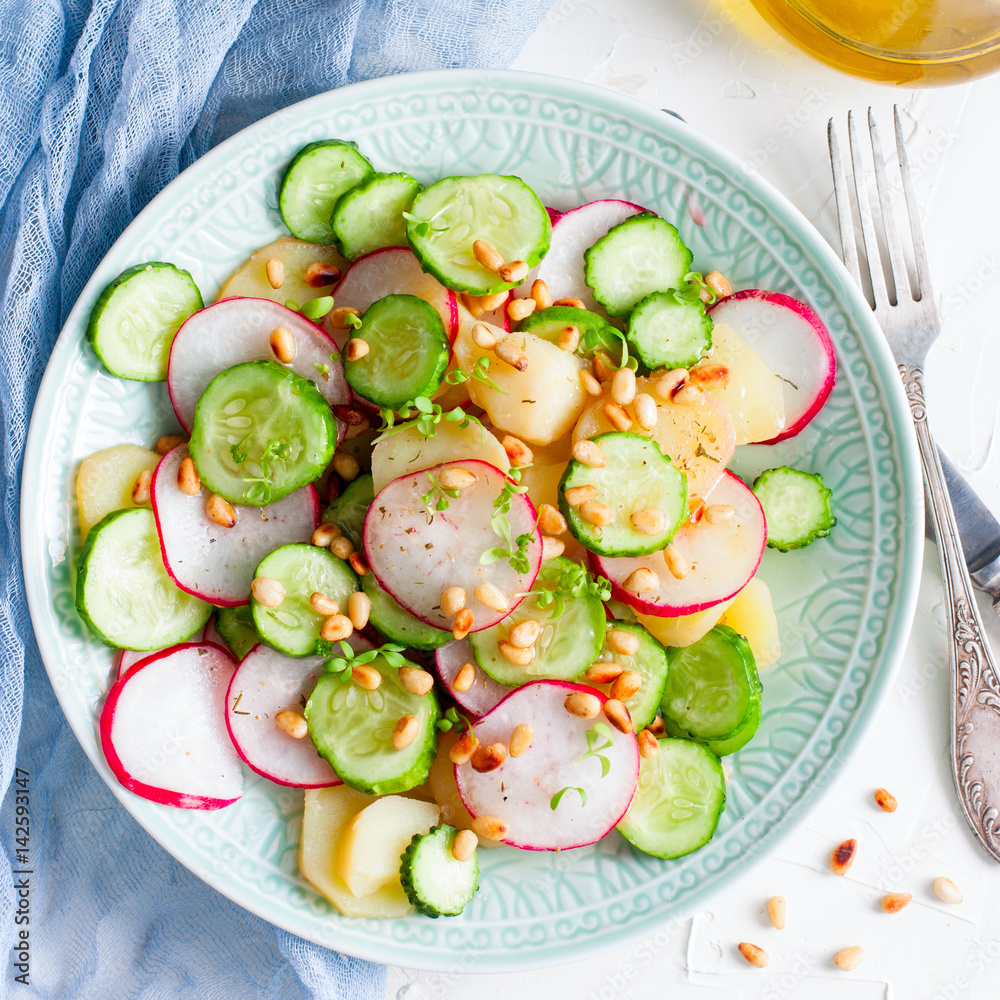 Salad from potatoes, radishes, cucumbers with pine nuts, top view, square
