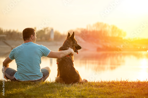 Photography Relaxed man and dog enjoying summer sunset or sunrise
