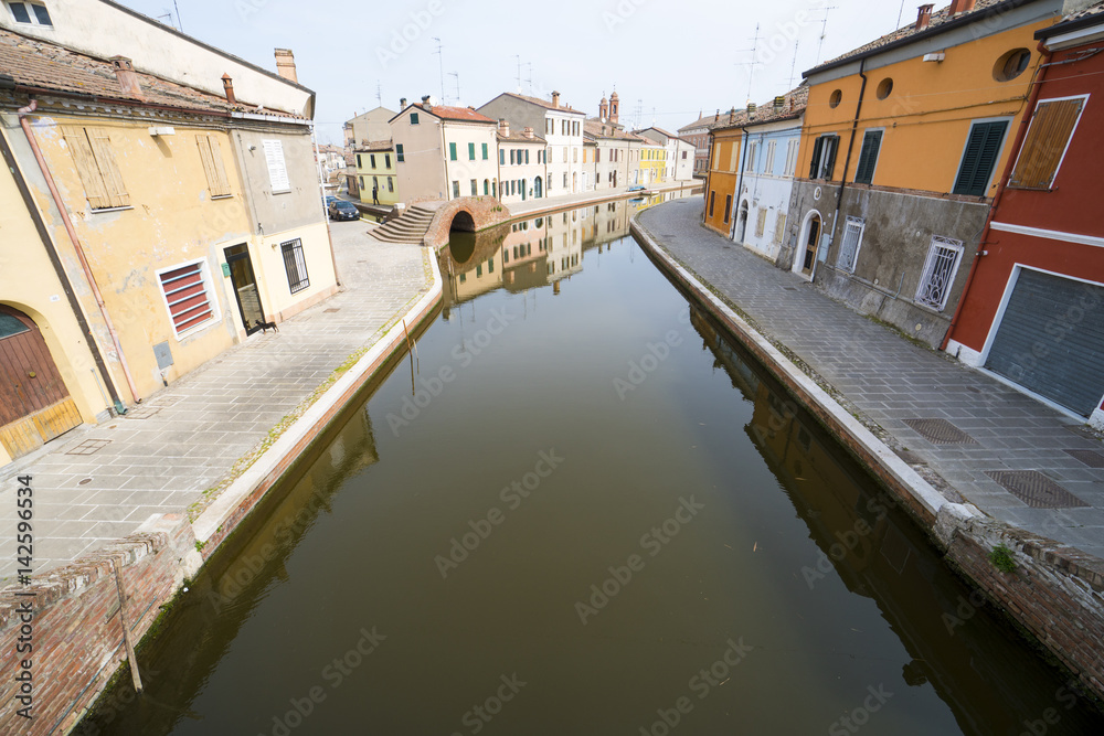 View of the small Italian town Comacchio (Ferrara, Emilia Romagna region): traditional colored houses and canal for boats.