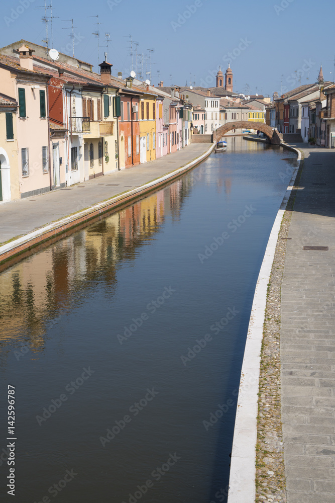 View of the small Italian town Comacchio (Ferrara, Emilia Romagna region): traditional colored houses and canal for boats.