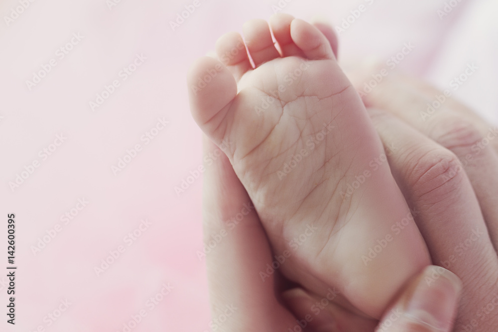 Closeup of mother hands holding cute tiny baby feet, showing baby foot. Selective focus. Toned. Closeup of mother hands holding cute tiny baby feet, showing baby foot. Selective focus. Toned.