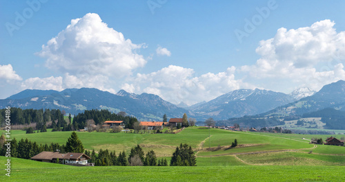 Village surrounded by green forests and snow covered mountains