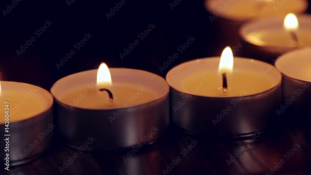 Lighted small candles with reflections in a dark background Lighted small candles with reflections in a dark background
