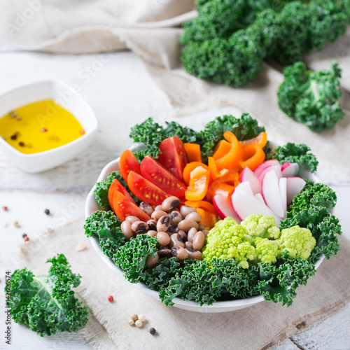 Healthy vegan buddha bowl with kale leaves and raw vegetables