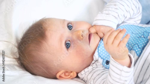 baby mit großen blauen augen und blonden haaren im bett