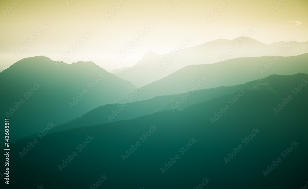 A beautiful, colorful, abstract mountain landscape with a hot summer haze in warm green tonality. Decorative, artistic look.