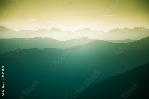 Fototapeta Naklejka Na Ścianę i Meble -  A beautiful, colorful, abstract mountain landscape with a hot summer haze in warm green tonality. Decorative, artistic look.