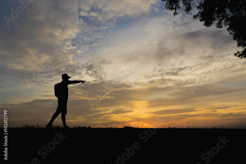 Silhouette of a man with hands point to sky in the sunset.