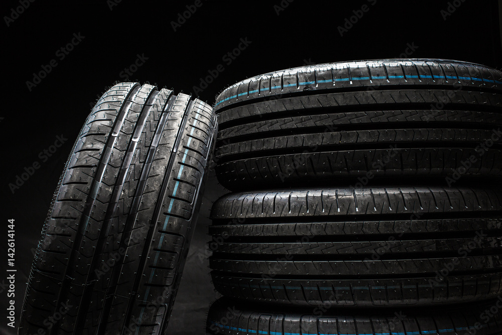 Stack of brand new high performance car tires on clean low-key black studio background Stack of brand new high performance car tires on clean low-key black studio background
