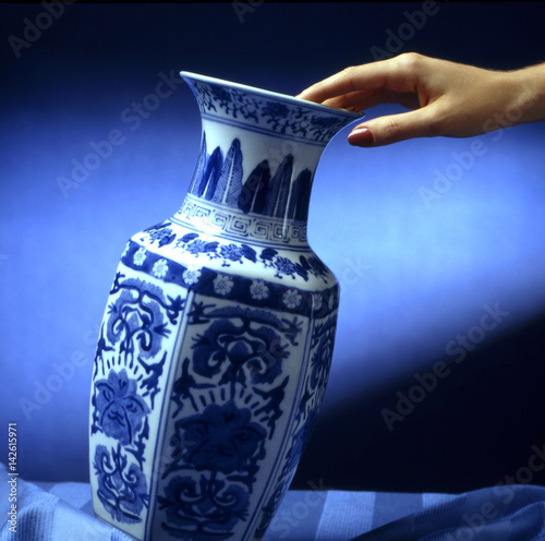 Canvas-taulu hand put a decorated ceramic vase on a table