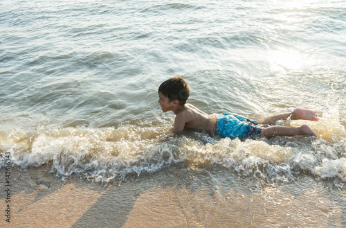 happy asian boy playing in the water waves at sea ocean © Phoompiphat