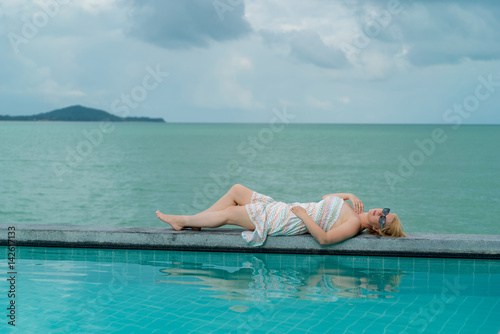 Young woman relaxing near pool at resort