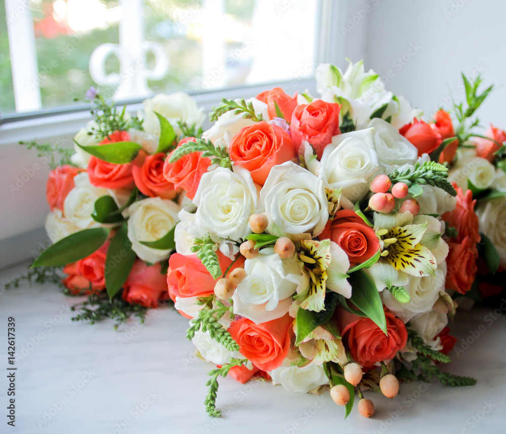 Wedding bouquet with orange and white roses on windowsill