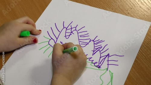 A child draws with colored pencil on paper. The early development of children and teaching them art. The desire to paint kids brought up from childhood.
