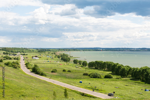 Romantic road into the distance, horizon, lake and green flat plain. Sports and recreation in auto kemping on Plesheevo lake resort.