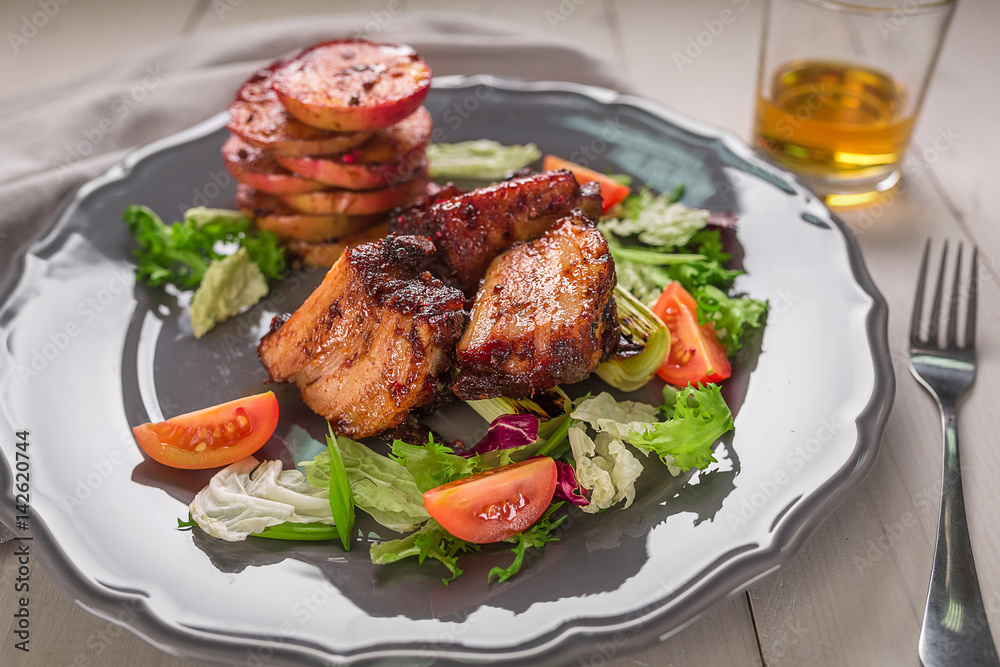 Hot Meat Dishes. Pork ribs grilled with salad and apples on a plate. Hot Meat Dishes. Pork ribs grilled with salad and apples on a plate.