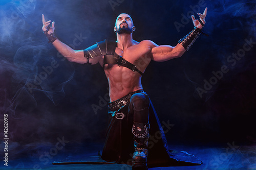 Handsome young sexy man with beautiful muscular chest in interesting costume on the scene