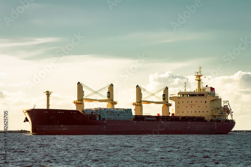 Red cargo ship (bulk carrier) moving entering the port of Riga